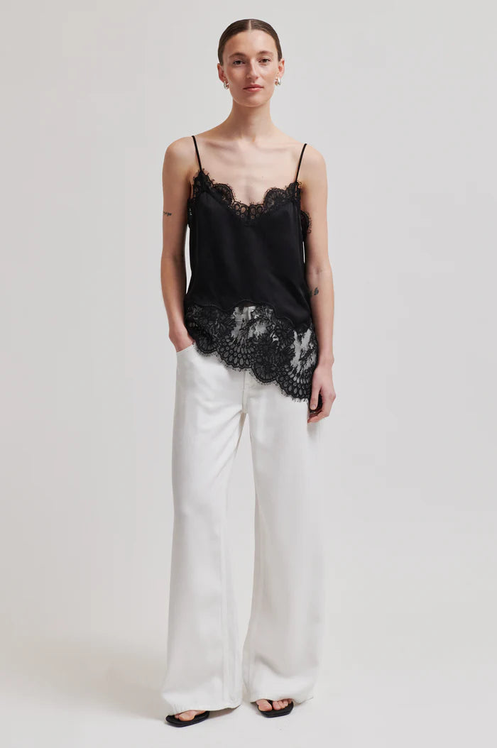 Woman wearing a asymmetrical black lace-trimmed top 