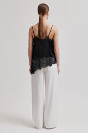 Woman wearing a asymmetrical black lace-trimmed top 
