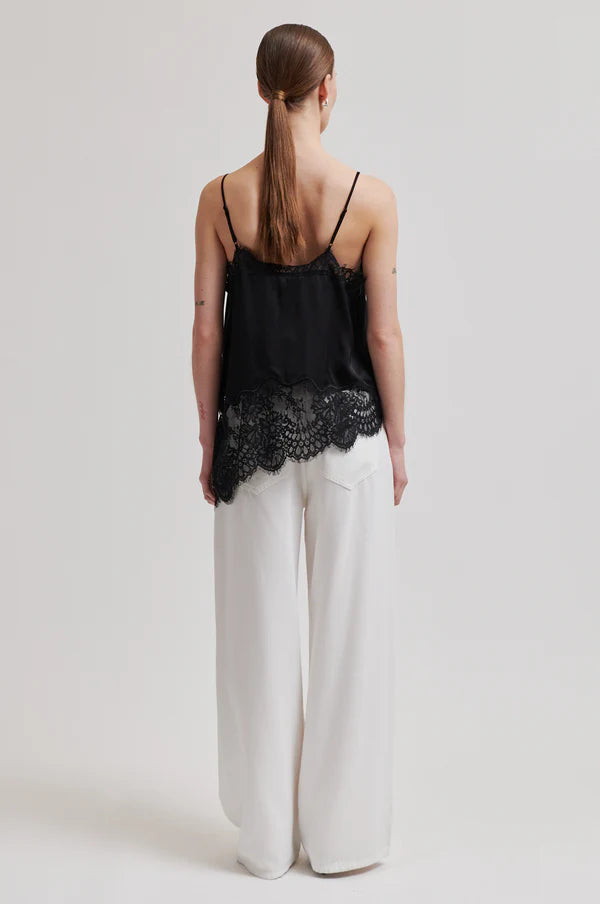 Woman wearing a asymmetrical black lace-trimmed top 