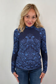Woman wearing a blue patterned long-sleeve mesh top against a plain background