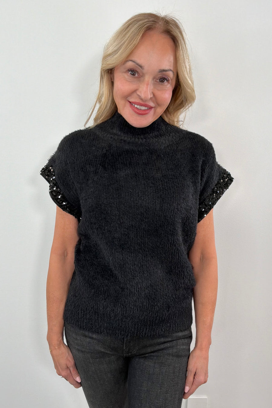 woman wearing a black fuzzy cap sleeve embellished sweater