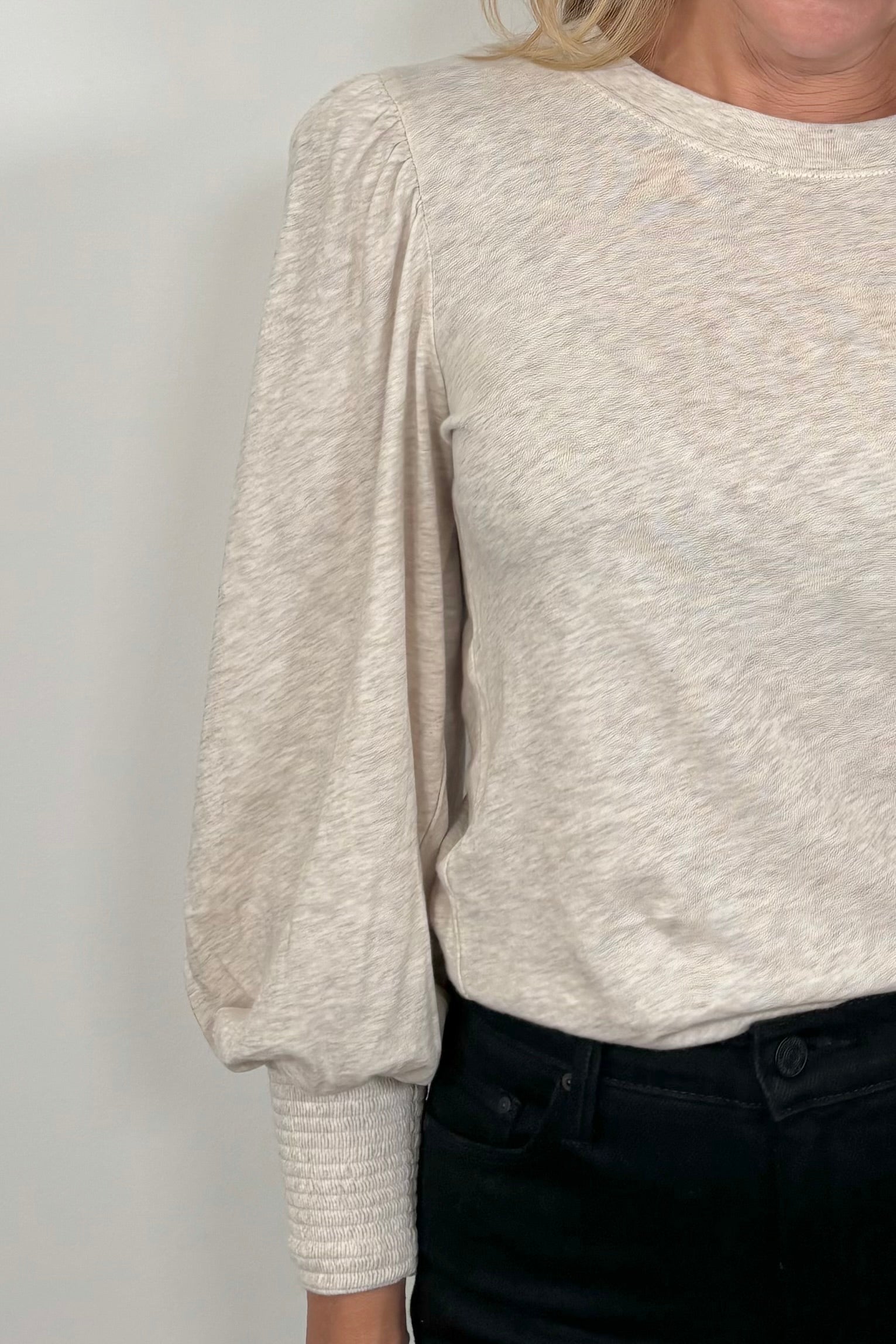 Close-up of a cuffed blouson sleeve of a beige top