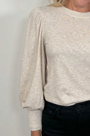Close-up of a cuffed blouson sleeve of a beige top