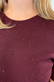 Woman wearing a maroon knit top 