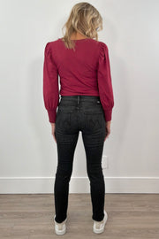 woman wearing washed black fitted jeans and a red top