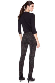 Woman wearing a black top and patterned leggings on a white background