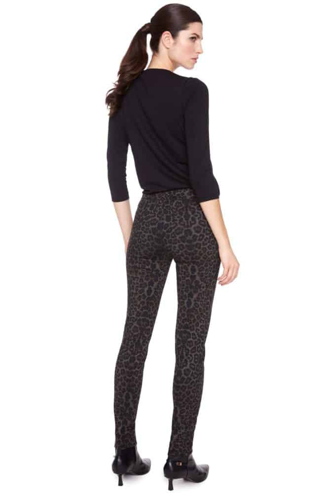 Woman wearing a black top and patterned leggings on a white background