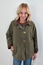 Woman wearing a green jacket with brown collar and cuffs