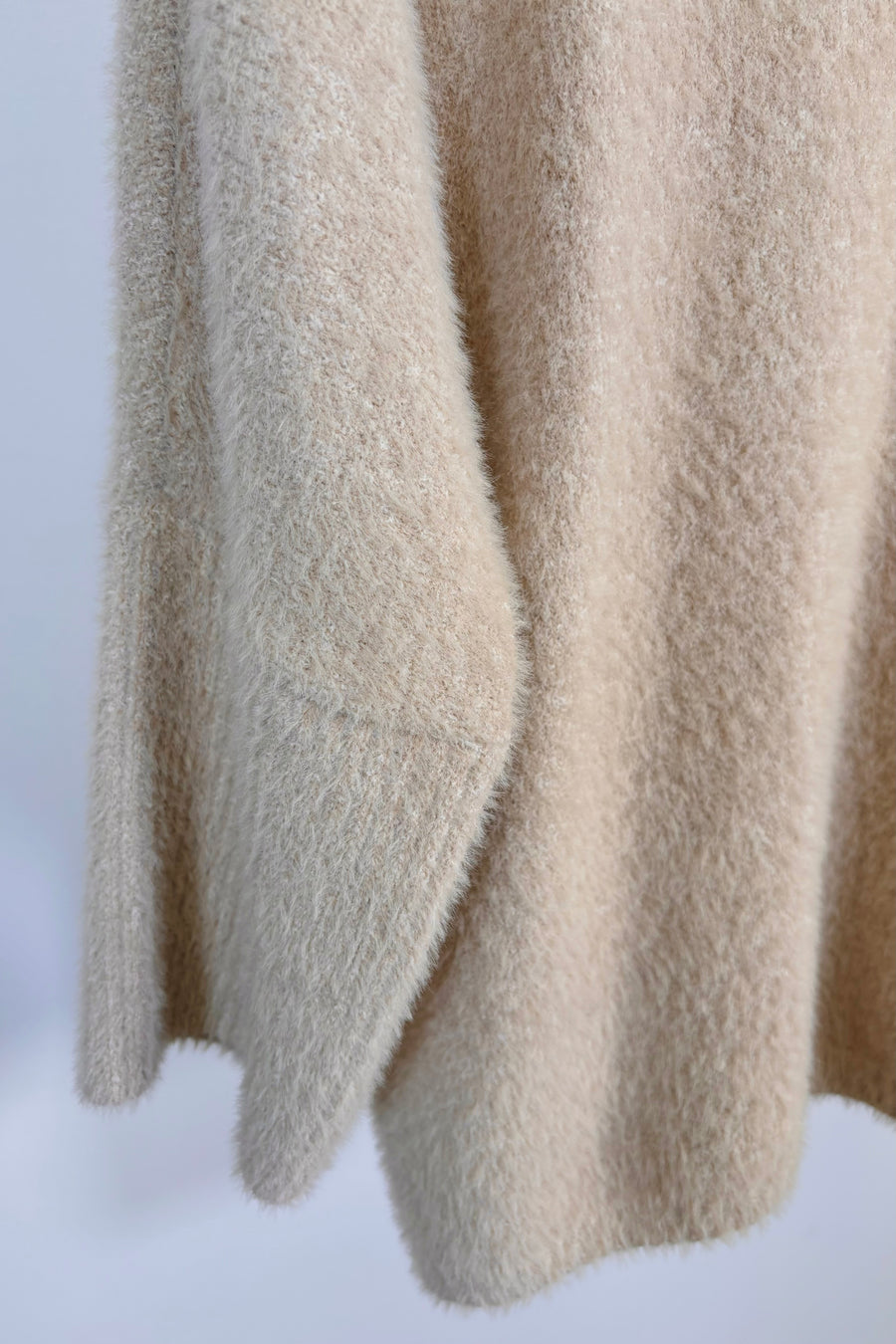 Close up of the half sleeve of a view of a mock neck hairy cream sweater