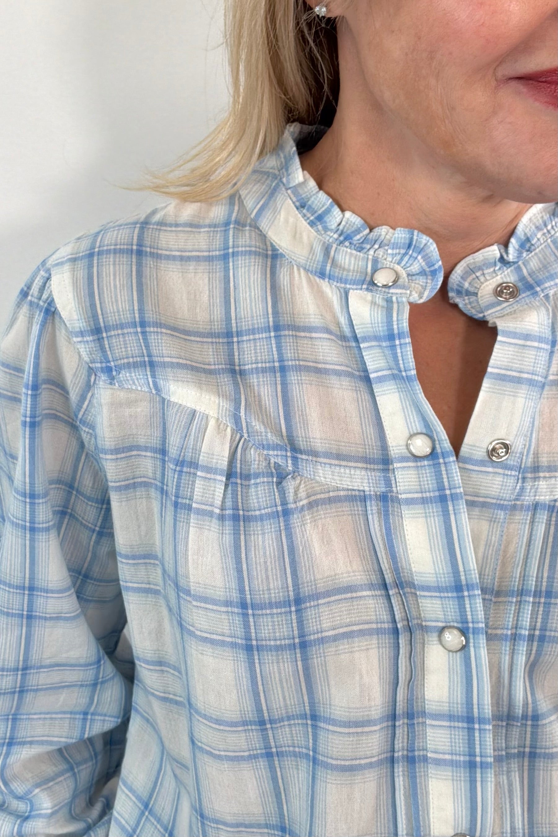 Close up of neck detail of Woman wearing a plaid button up shirt in blue and white