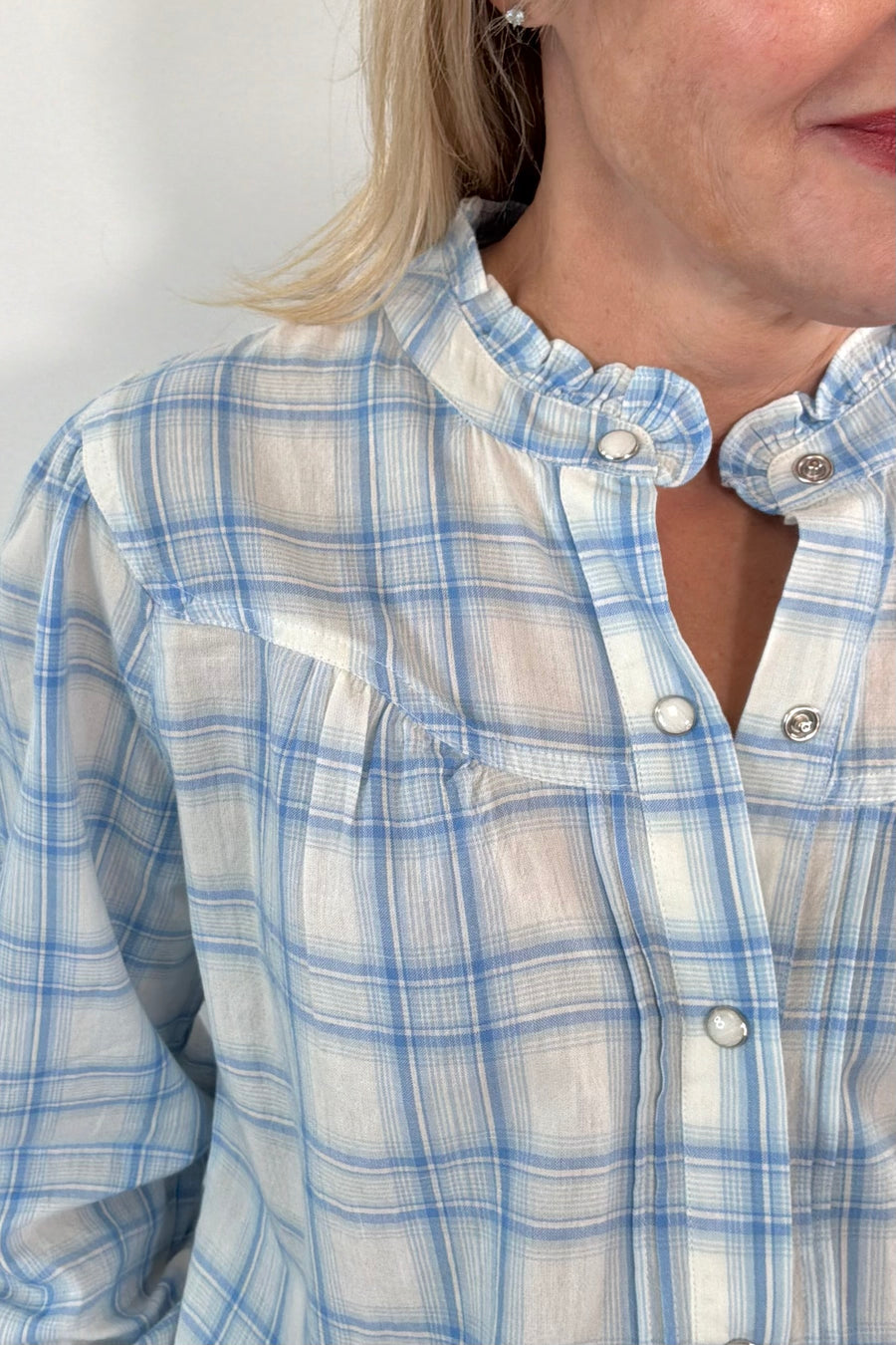 Close up of neck detail of Woman wearing a plaid button up shirt in blue and white