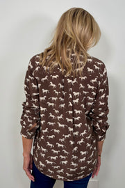 Back view of woman wearing a brown silk blouse with a white horse pattern all over 