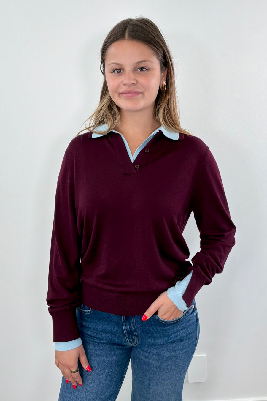 Woman wearing a burgundy sweater with a blue collar