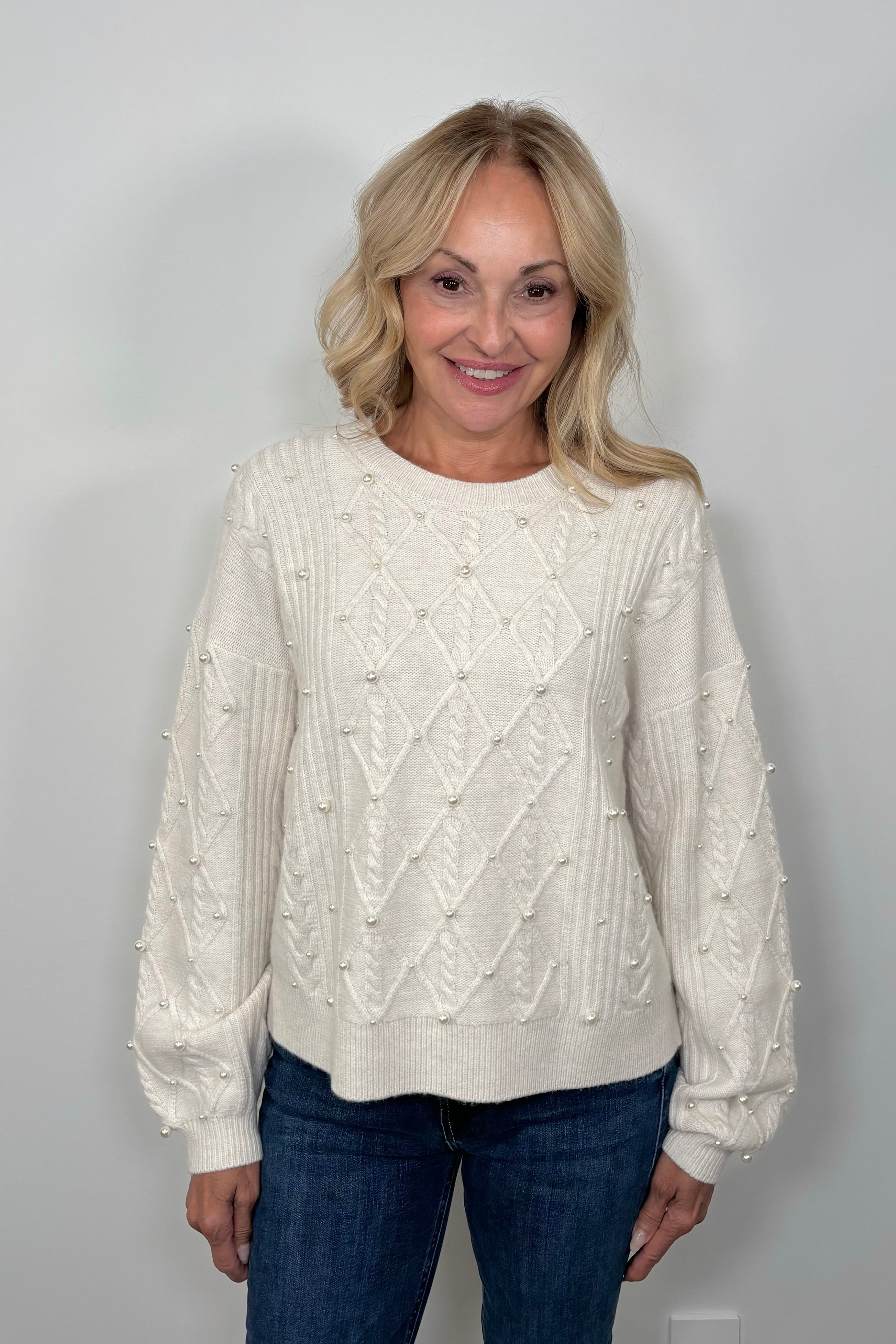 Woman wearing a white sweater with pearl embellishments 