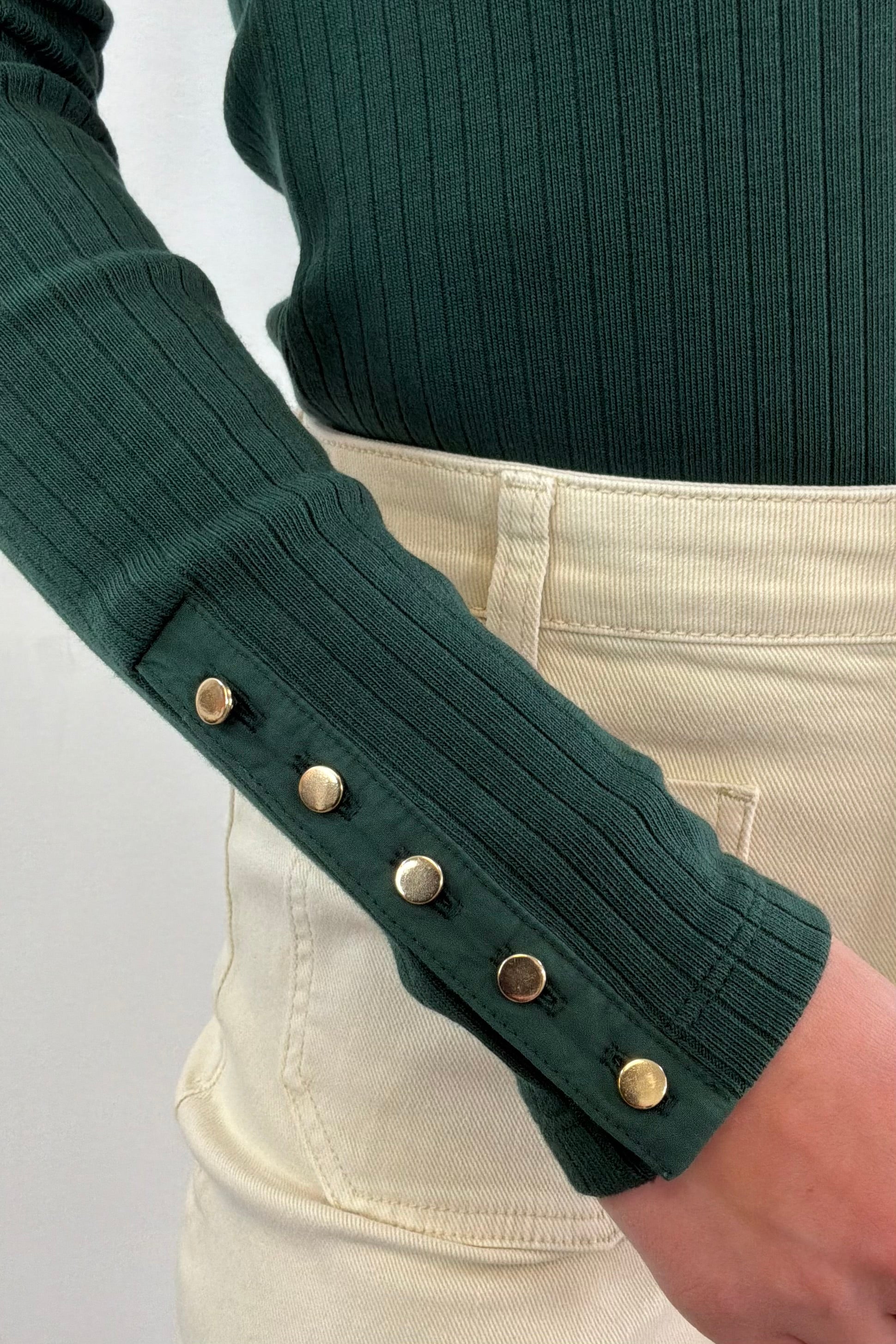 Close up of gold hardware details on Woman wearing a green knitted long sleeve 