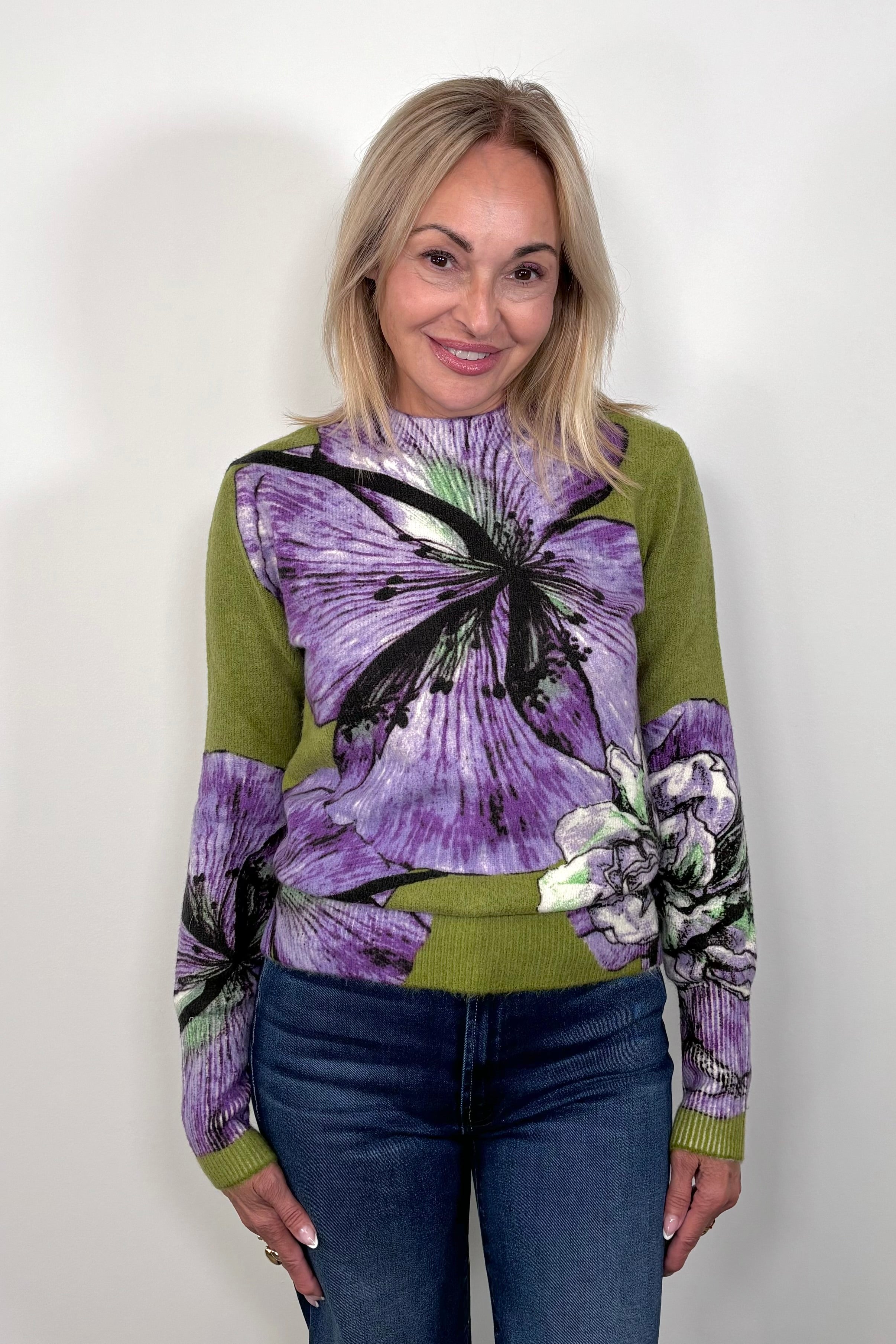 Front view of woman wearing a green sweater with purple orchids all over