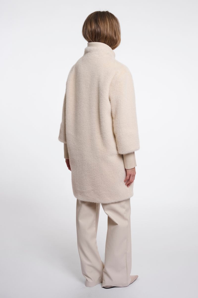 Woman wearing a beige fluffy coat. 