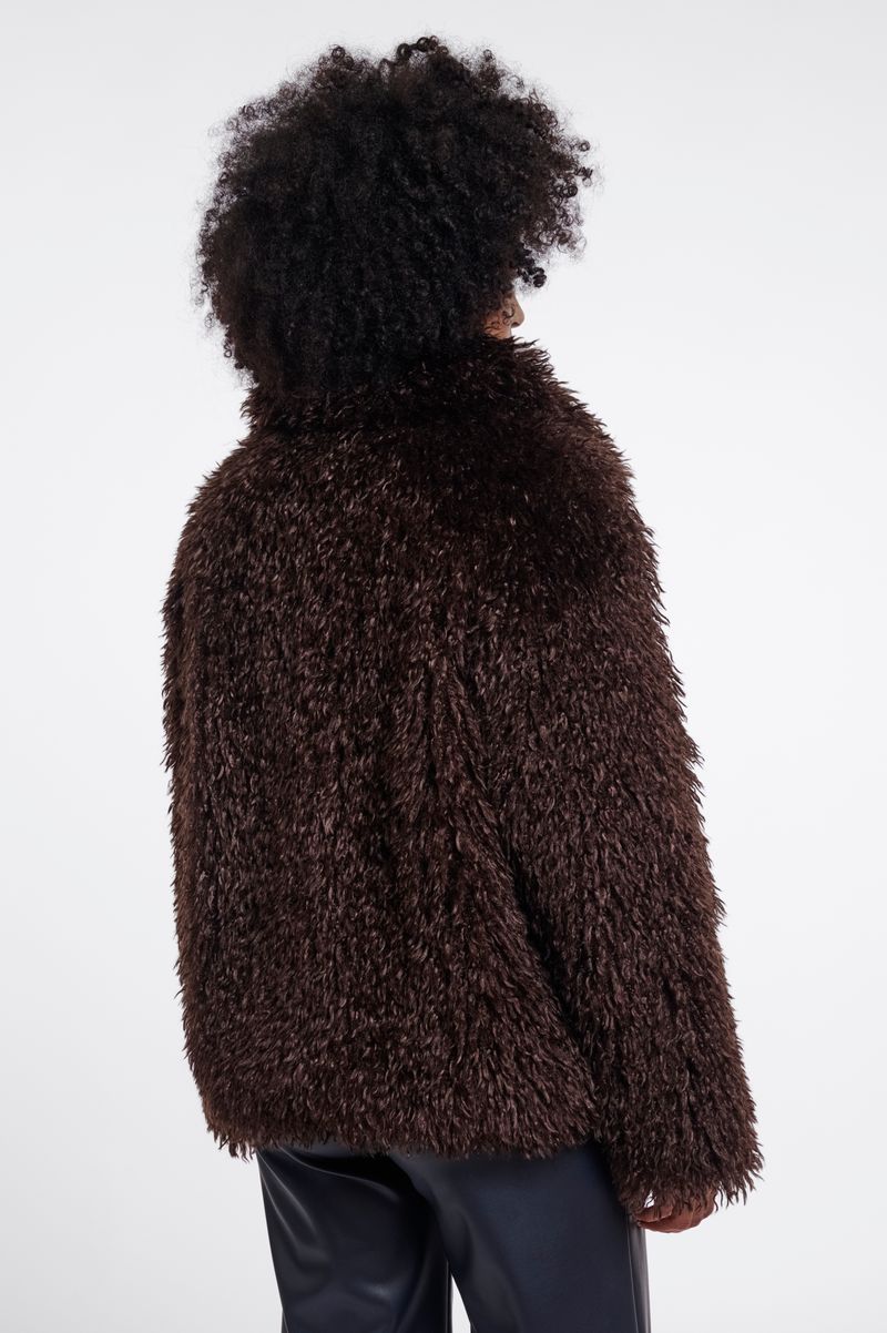 Woman wearing a brown faux fur jacket in chocolate brown. 