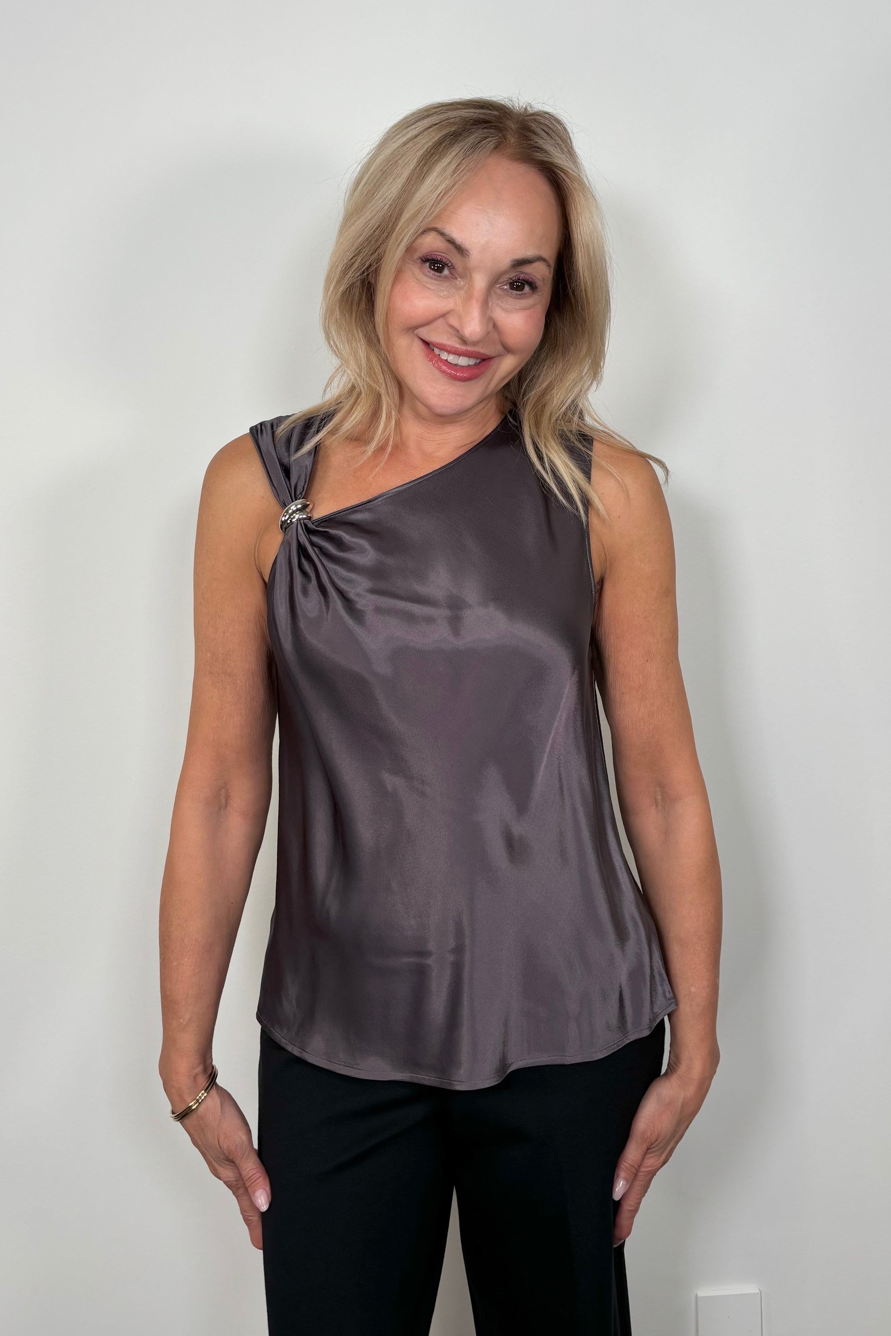 Front view of woman wearing a deep metallic gray satin tank top with a silver metal detail