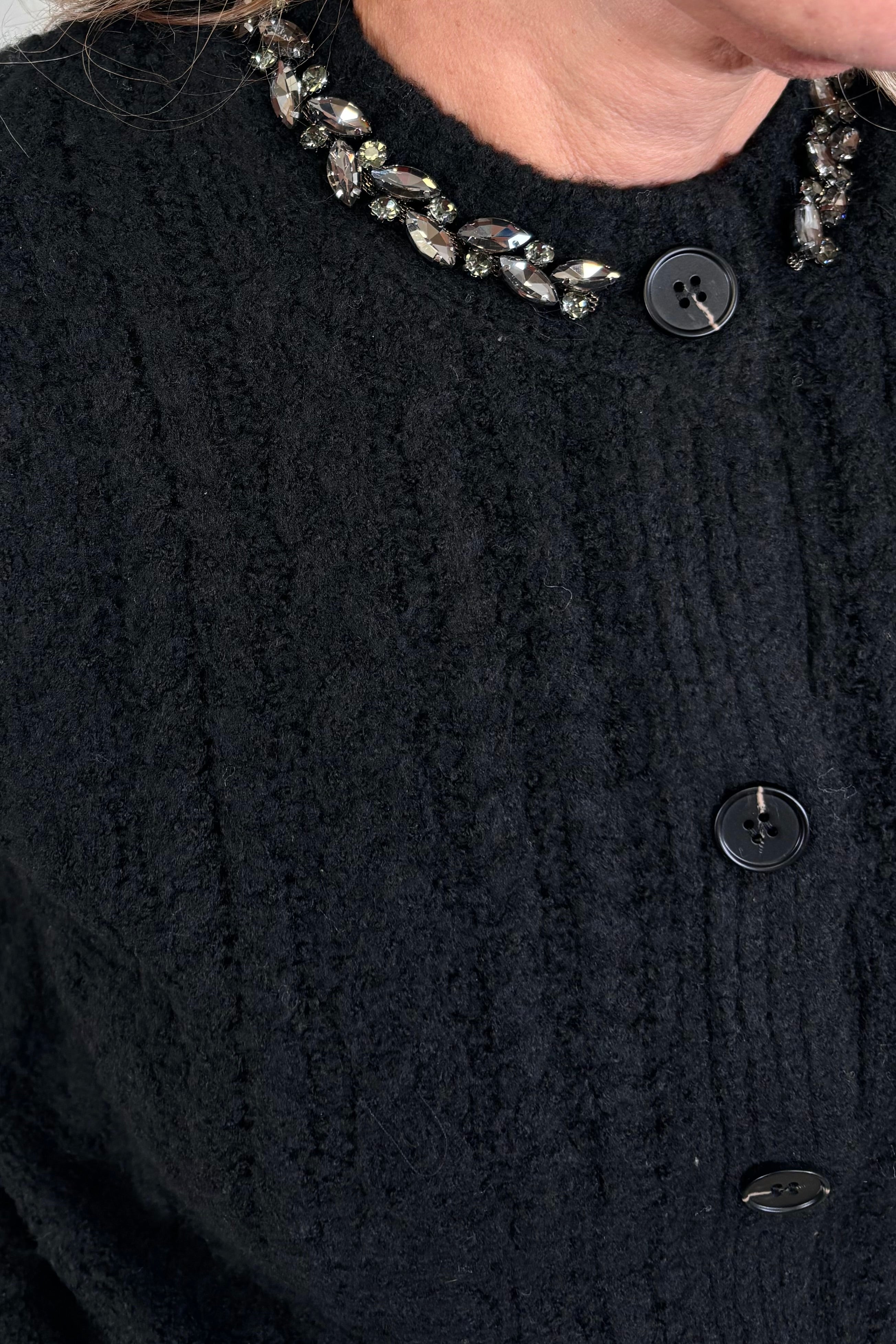 close-up of a black knit button up cardigan with embellishments in the collar