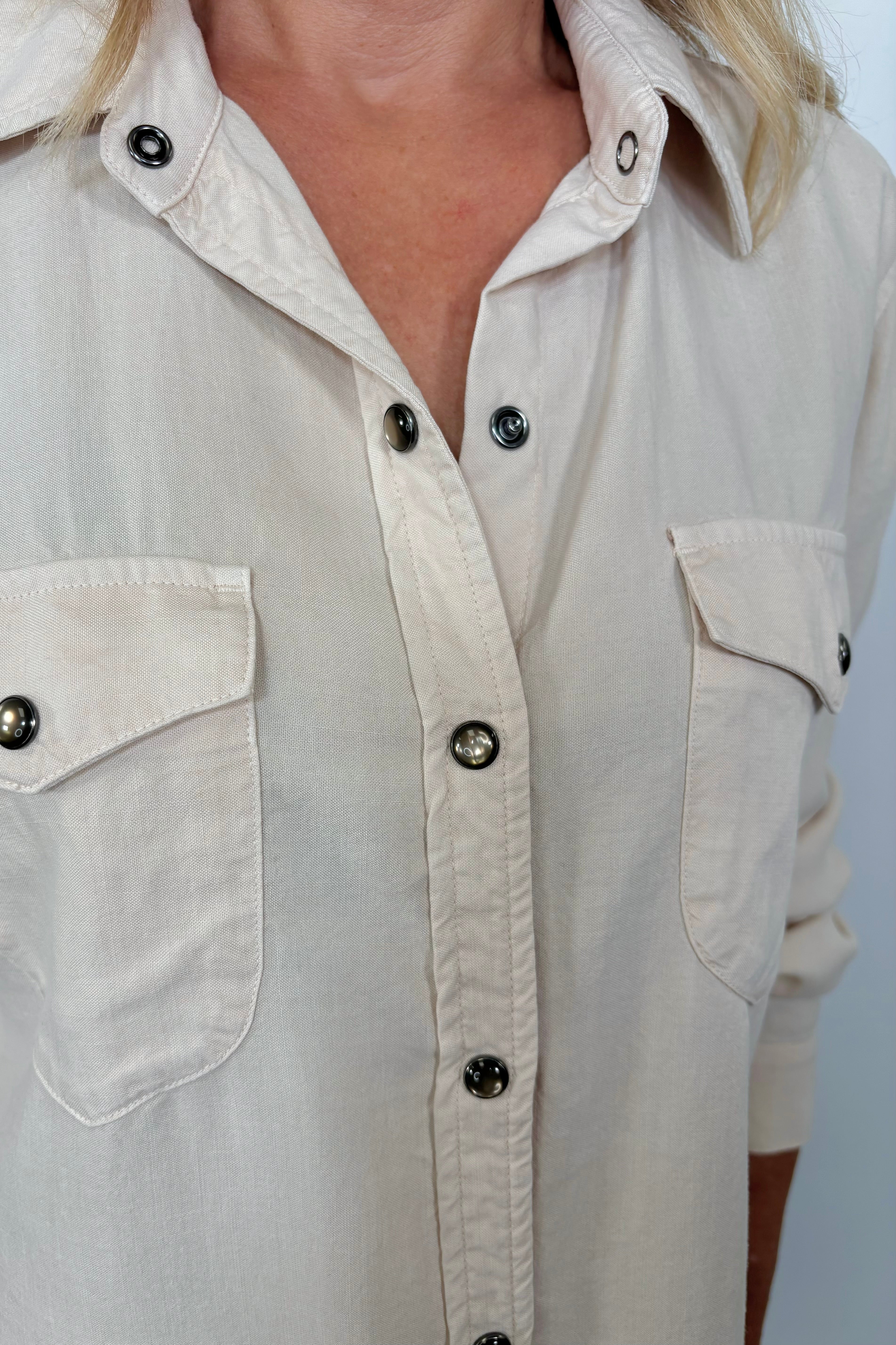 Close-up of the neckline of woman wearing a western snap off-white shirt 
