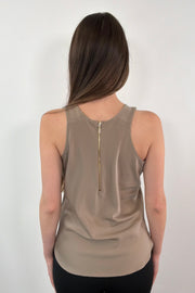 woman wearing a greige sleeveless satin zip-up top 