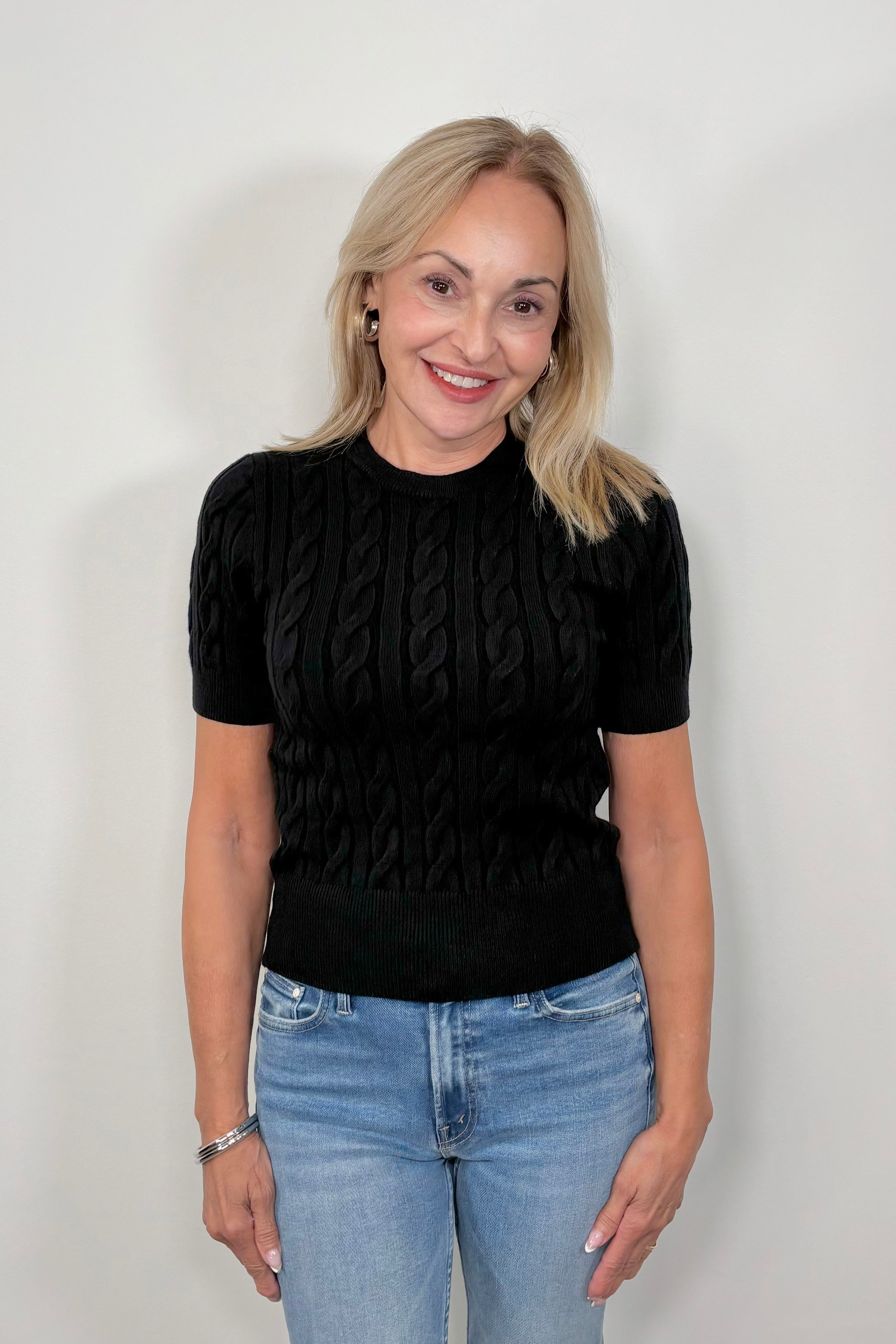 Front view of woman wearing a black coloured cable knit top