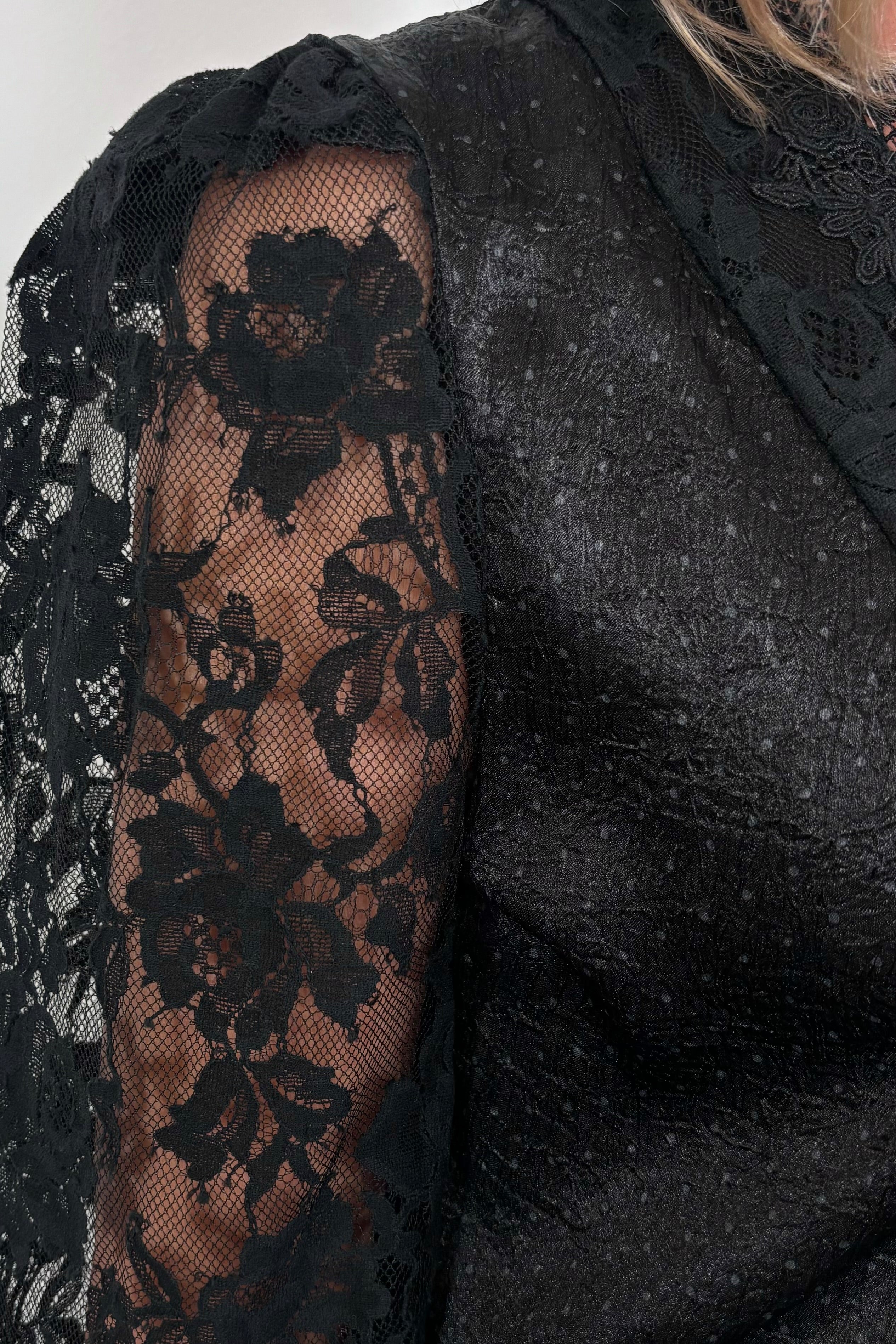close-up of the lace sleeve of a black satin top 
