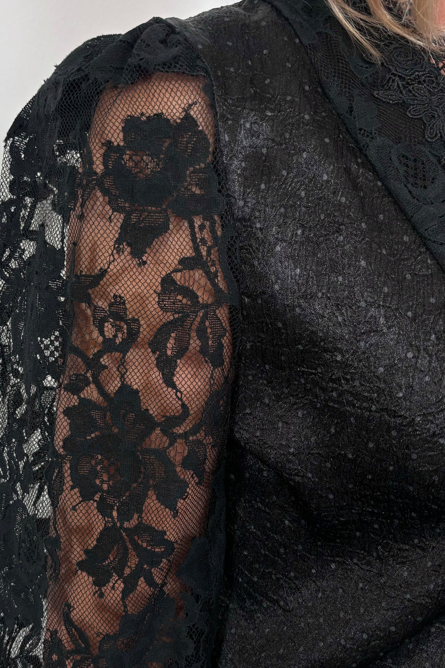 close-up of the lace sleeve of a black satin top 