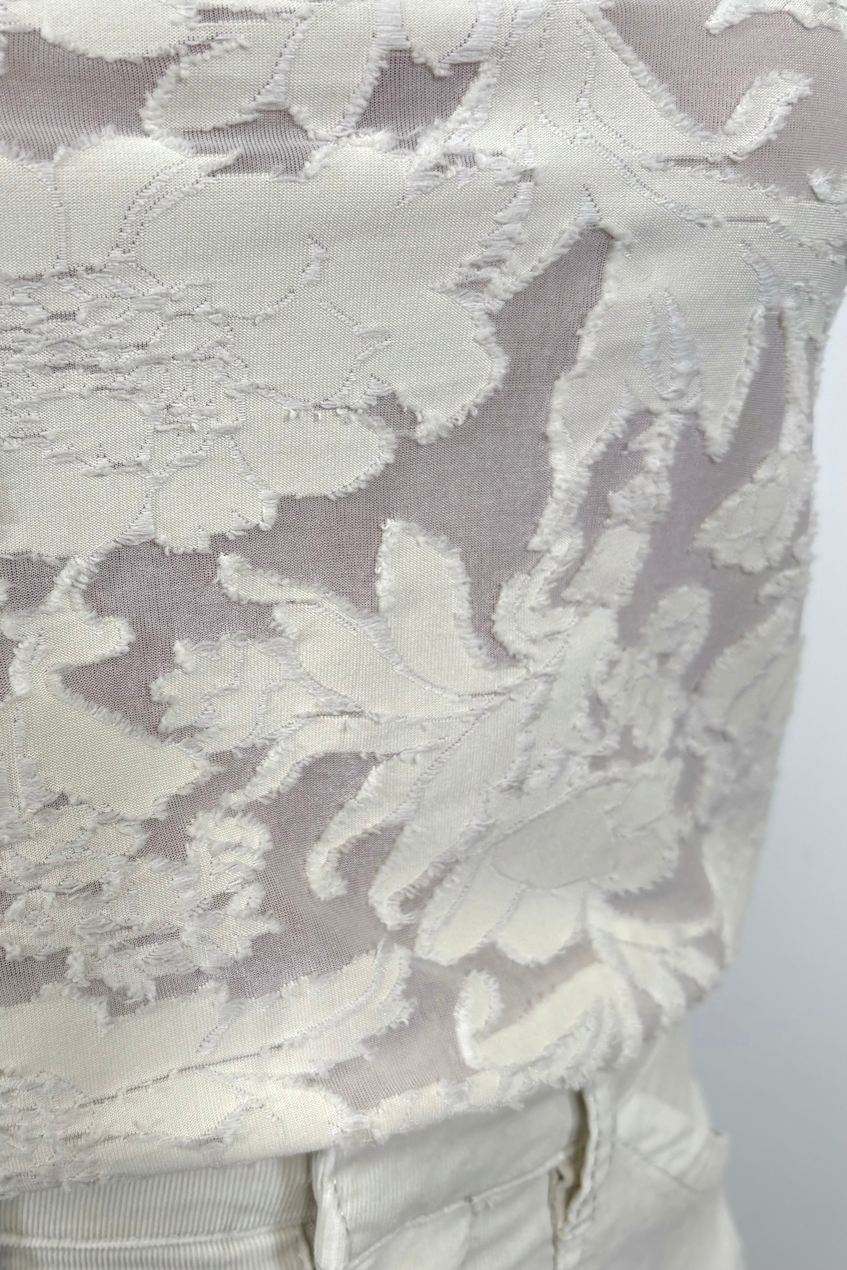close up of an off white lace-like long sleeve