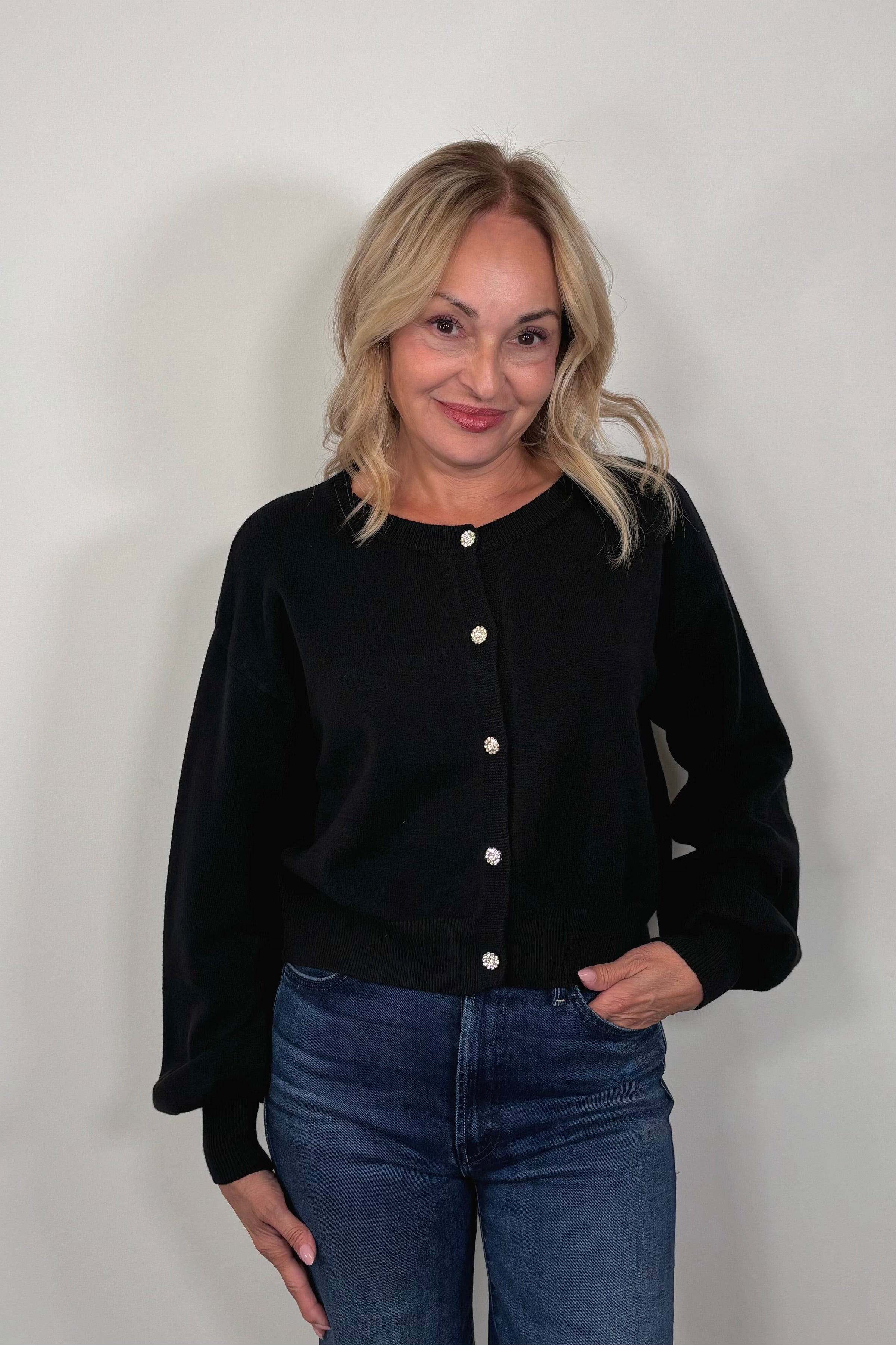 woman wearing a black button up cardigan with crystal buttons