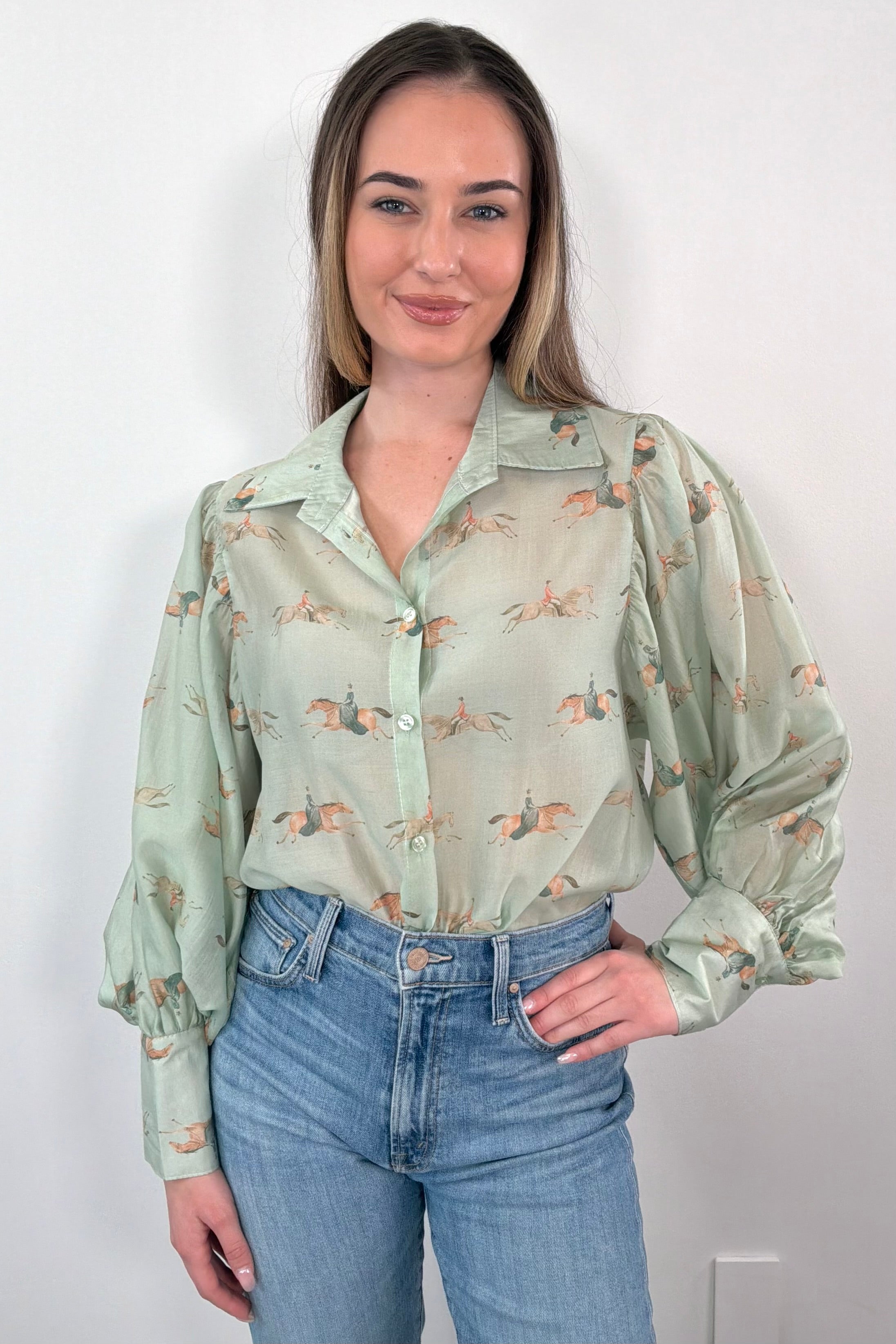 Woman wearing green long sleeve blouse with pony graphic on shirt