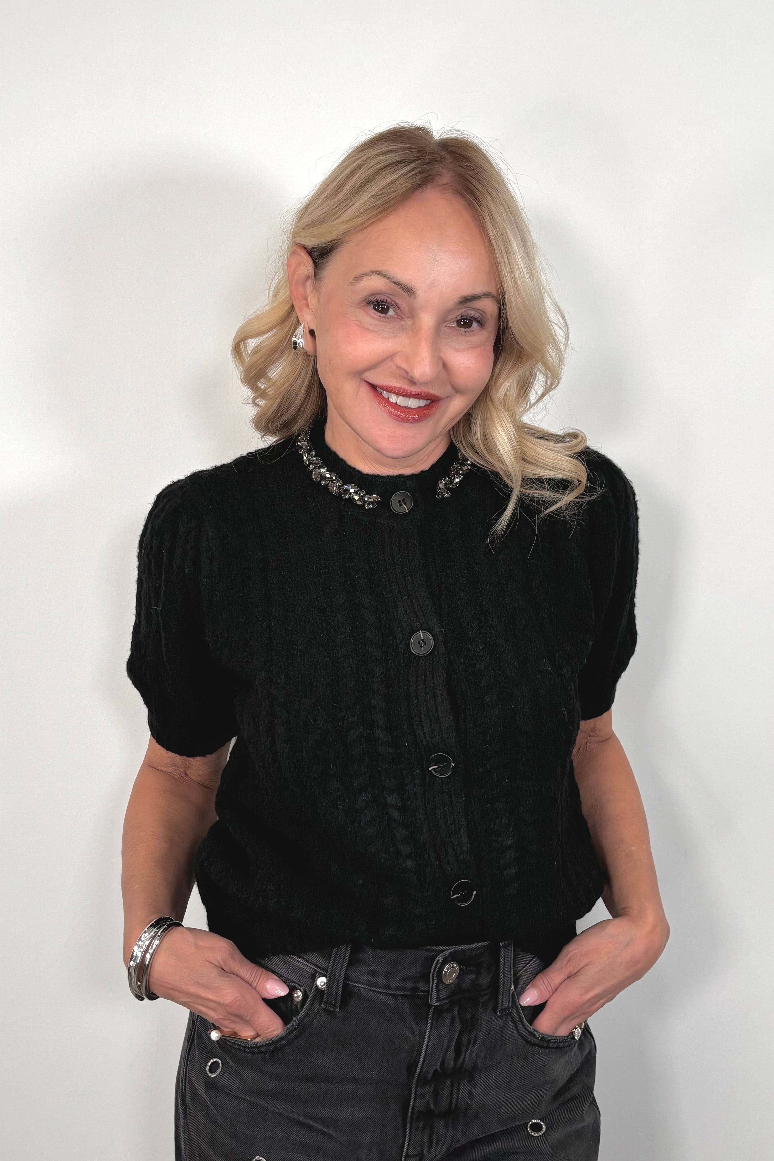 woman wearing a black knit button up cardigan with embellishments in the collar