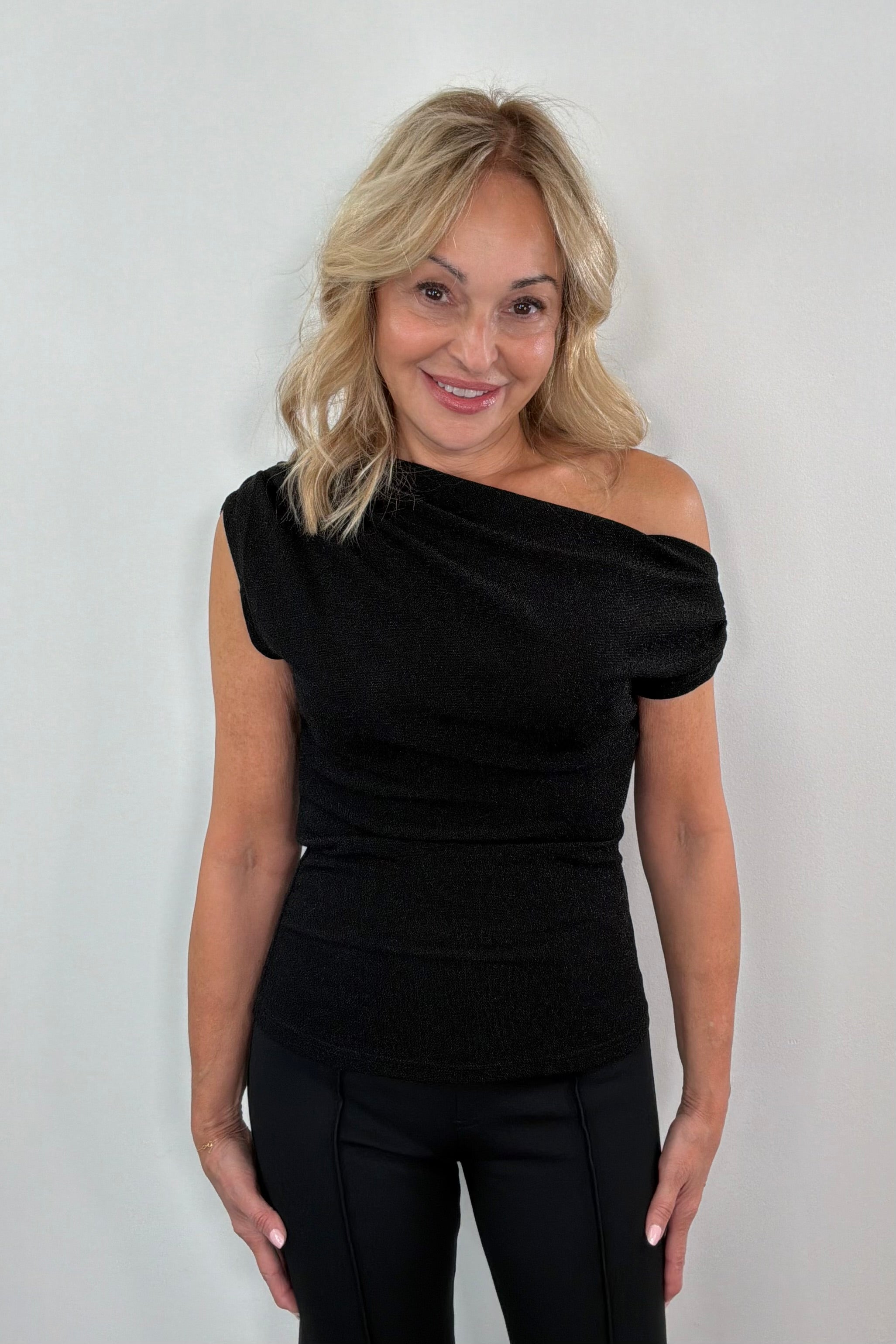 Woman wearing a black off-shoulder top against a white background