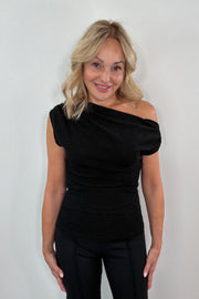 Woman wearing a black off-shoulder top against a white background