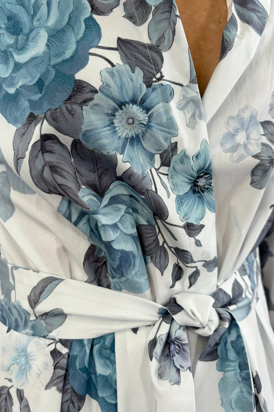 Close up of Woman wearing a white cotton dress with light blue floral print all over