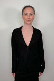 Front view of woman wearing a black knitted jacket and a pink turtleneck tank top