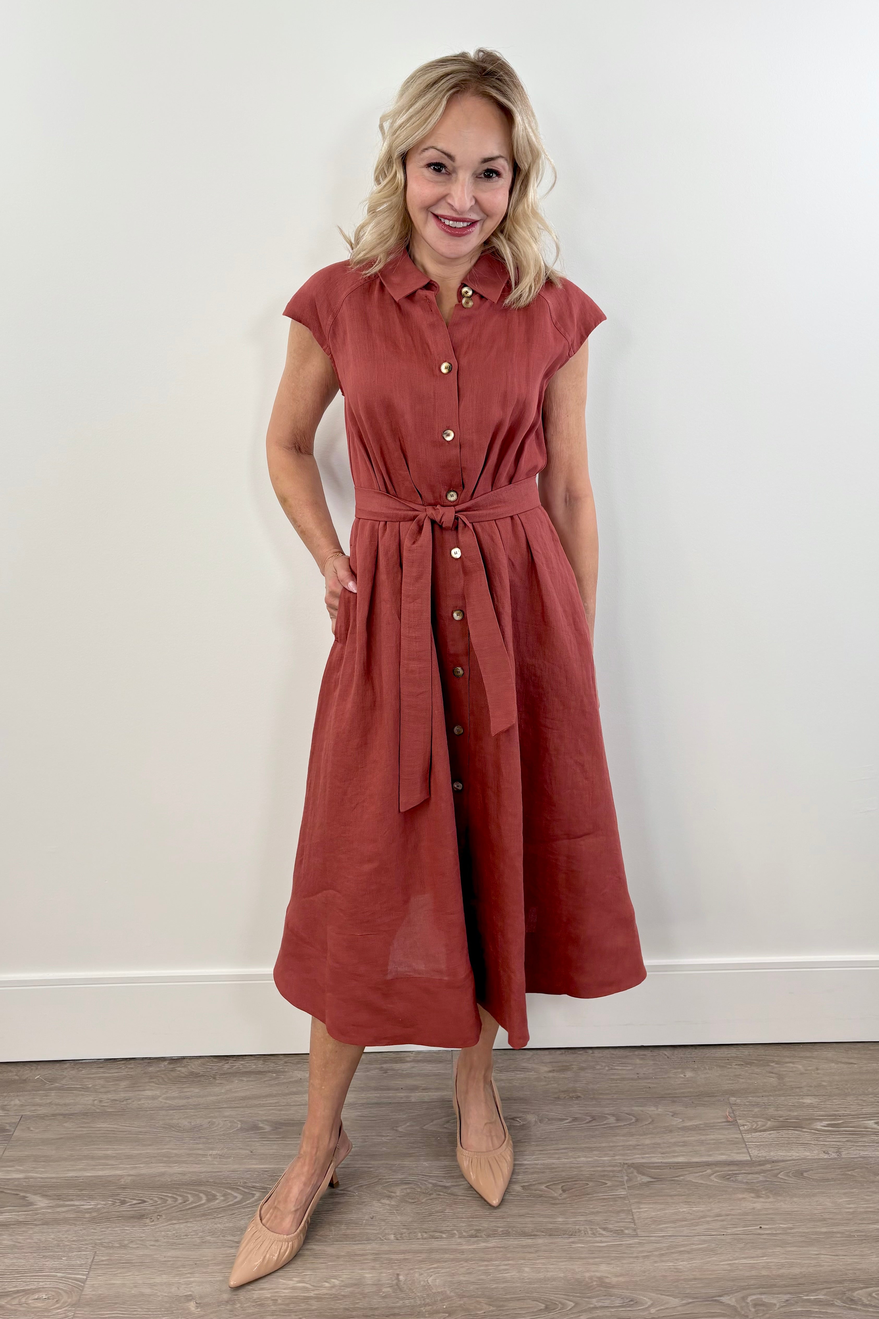 Woman wearing a wine red linen short sleeve belted dress with a button up detail in the front.