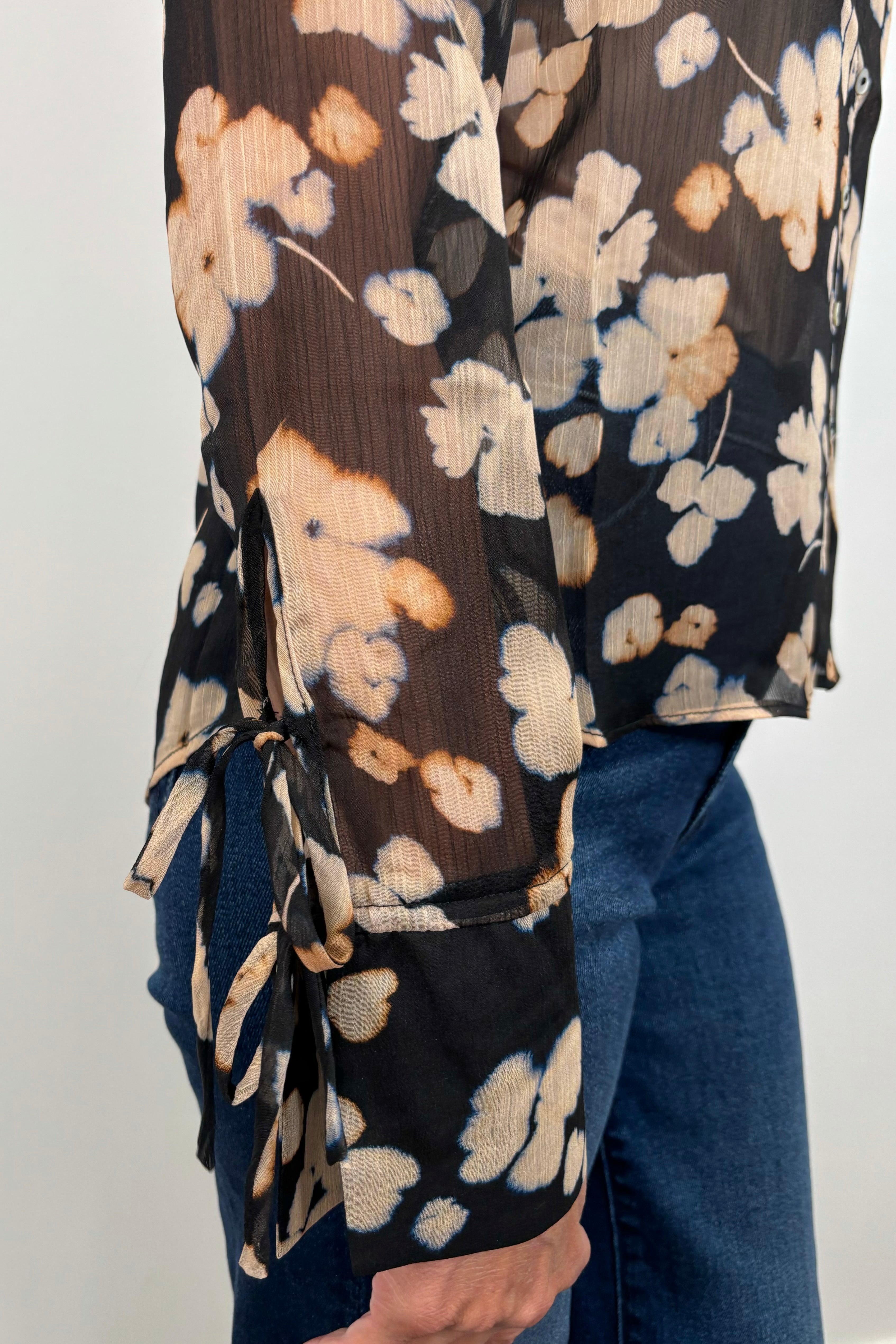 Close-up view of the sleeve of a sheer long sleeve floral blouse