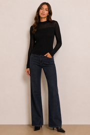 Woman wearing a black long-sleeve knit top. 