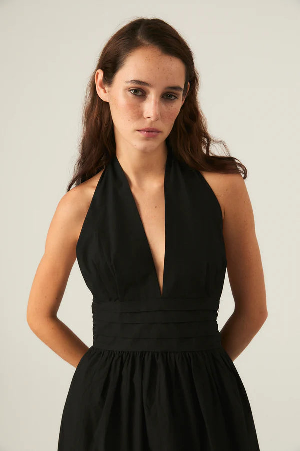 Woman wearing a black halter neck dress. 