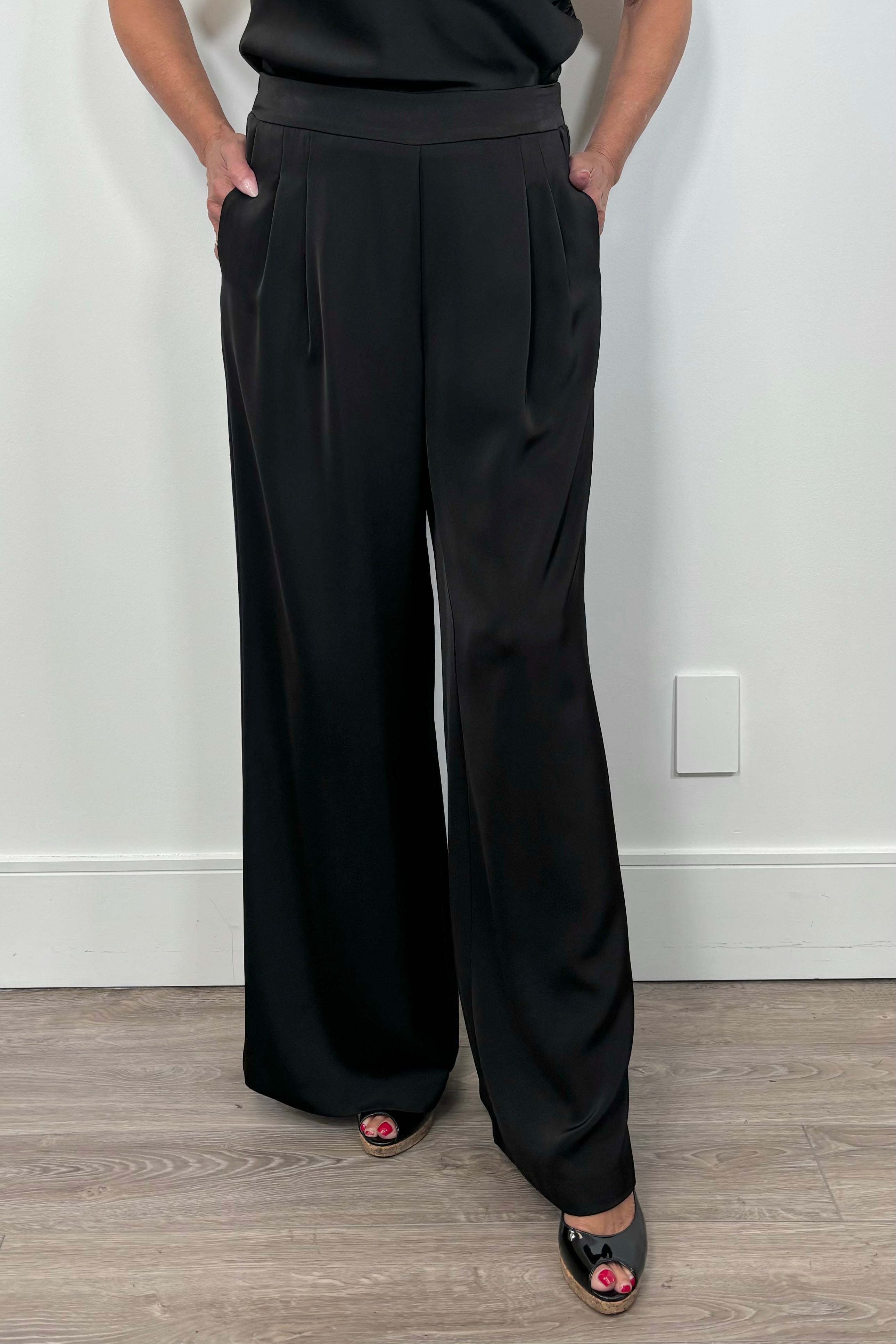 Front view of woman wearing a satin black wide leg pant