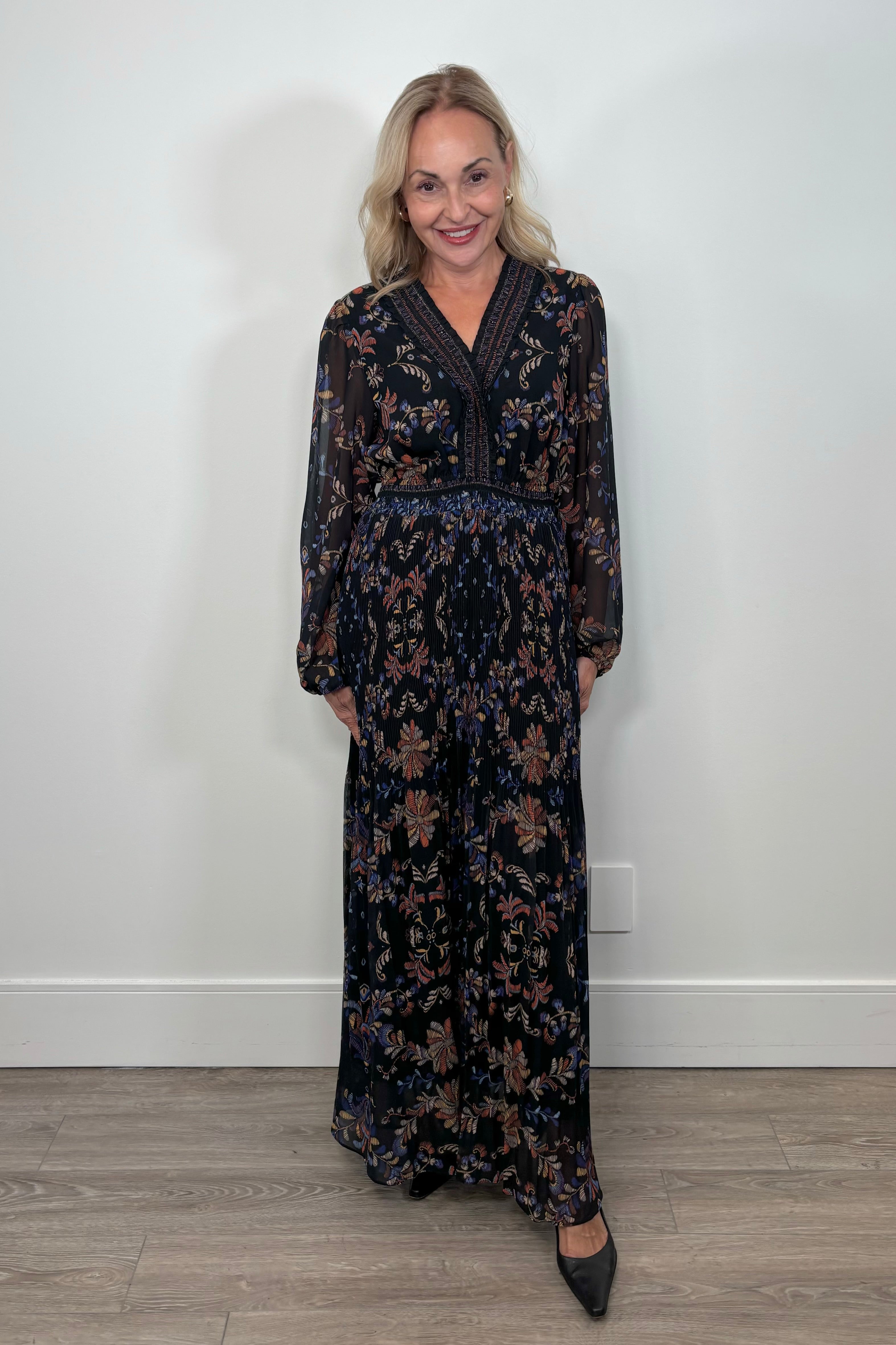Front view of woman wearing a black v-neck maxi dress with a colourful pattern