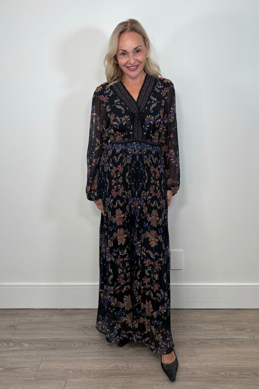 Front view of woman wearing a black v-neck maxi dress with a colourful pattern