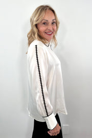 woman wearing a silk cream blouse with black trimming