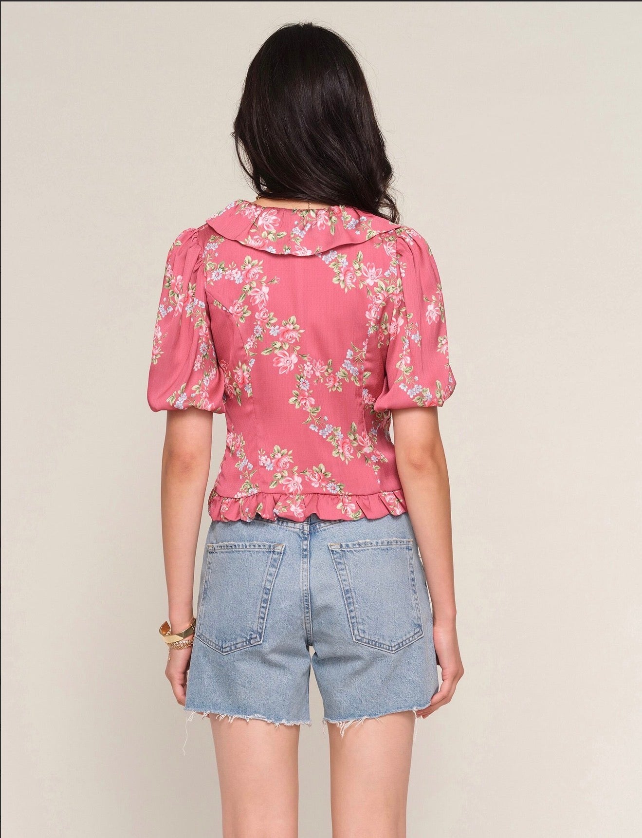 Back view of woman wearing a light red ruffle top with floral print allover