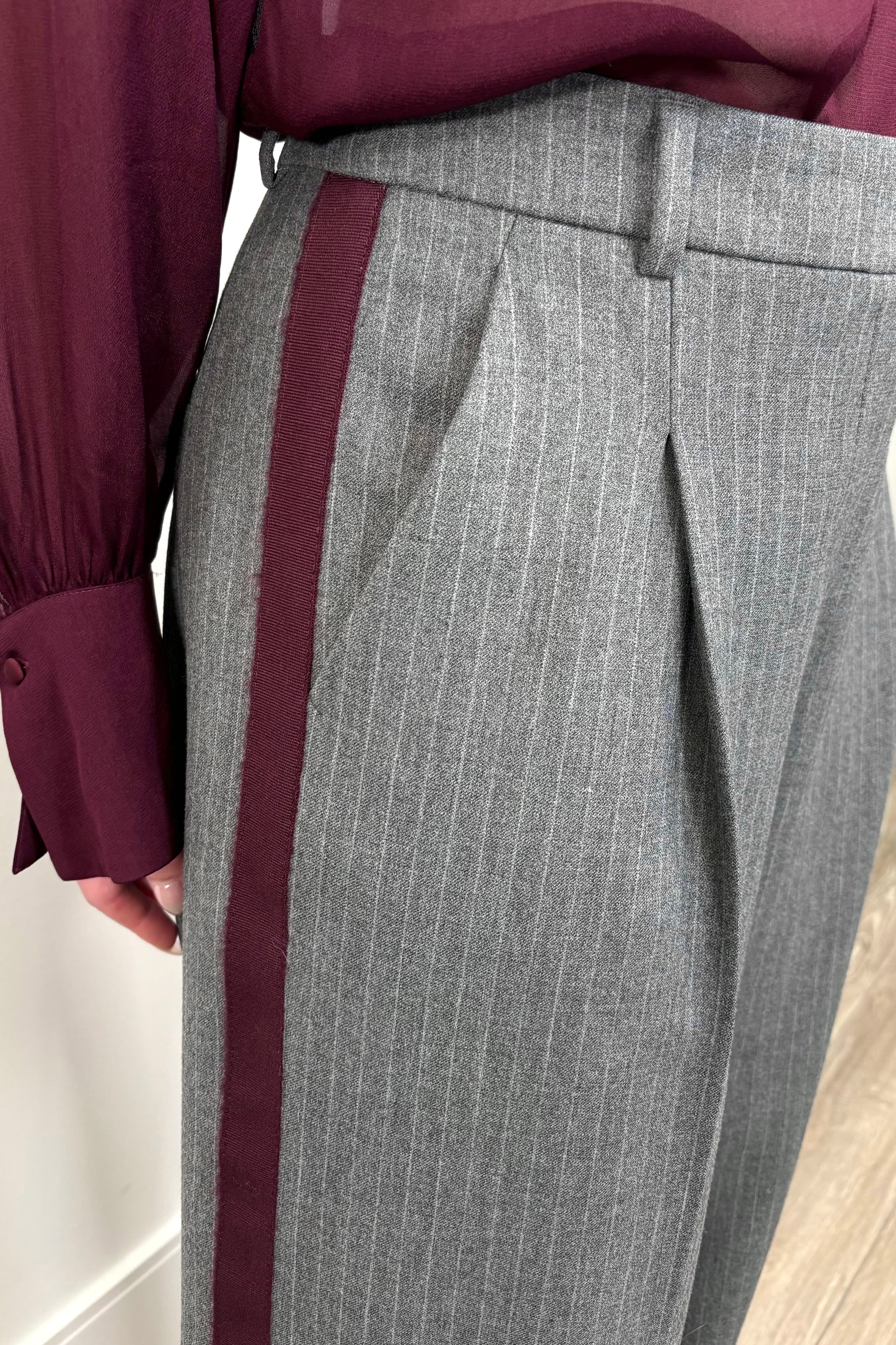 Close up view of woman wearing a gray pinstripe wide leg pant with a burgundy line down the leg