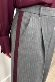 Close up view of woman wearing a gray pinstripe wide leg pant with a burgundy line down the leg