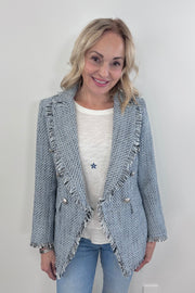 Woman wearing a light blue tweed blazer with silver buttons