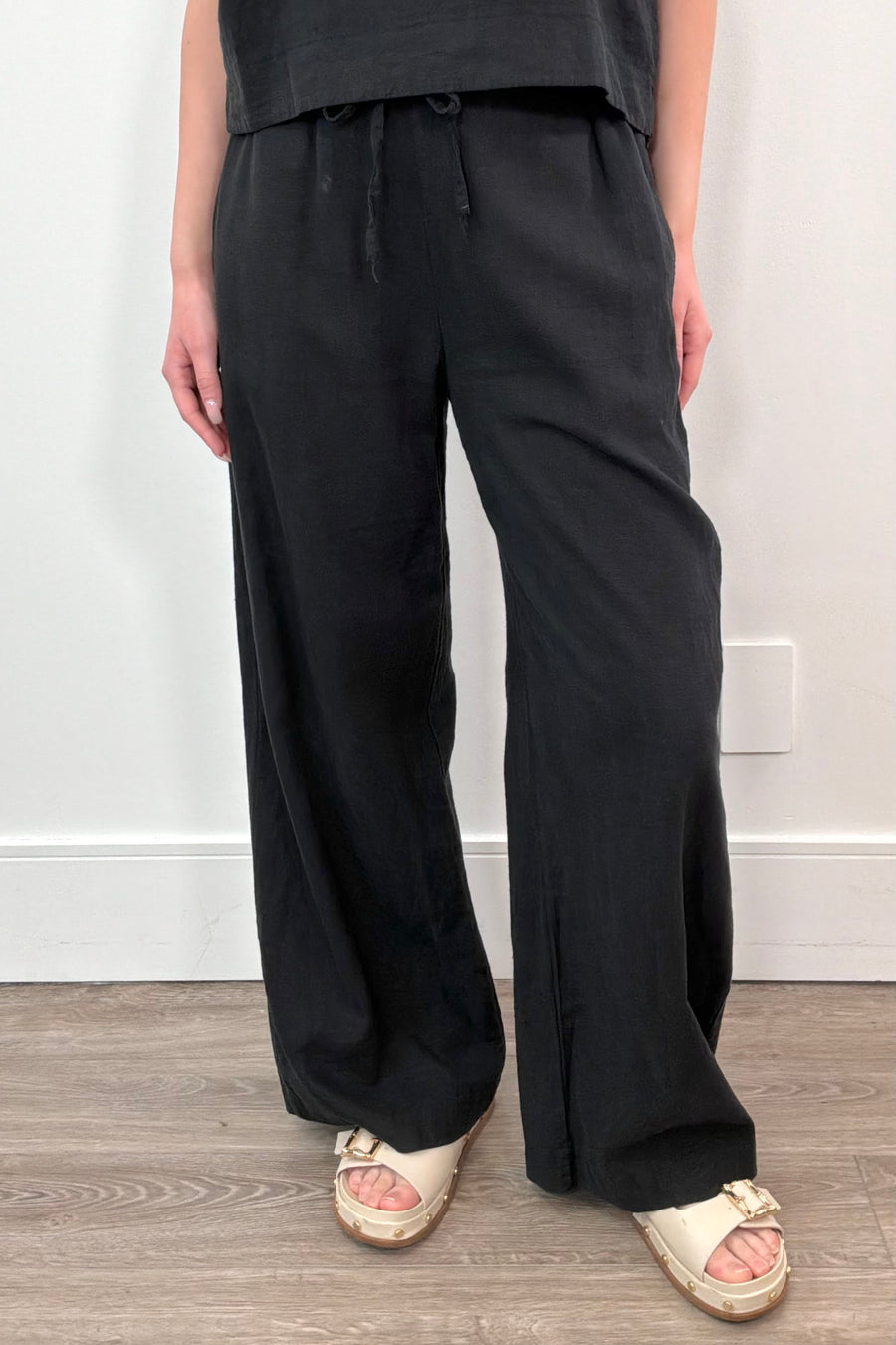 Woman wearing linen wide leg pants with drawstring waistband in black